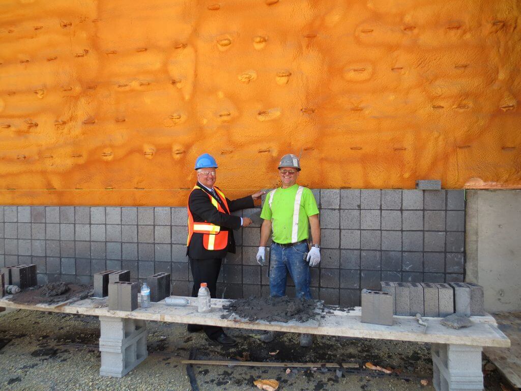 Terry Sheehan, federal MP for Sault Ste. Marie  laying a brick on the new Plaza Traffic Building.